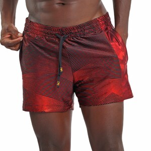 May include: Red and black striped swim trunks with a gold drawstring. The trunks have a wavy pattern.