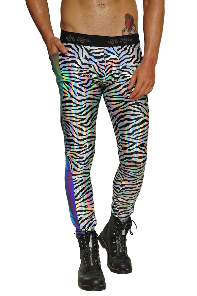 May include: Black and white zebra print leggings with a iridescent rainbow stripe down the side. The leggings are made of a shiny, stretchy material. The model is wearing black boots.