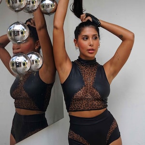 Peut inclure: Une femme portant un haut court noir et marron &agrave; imprim&eacute; l&eacute;opard avec un panneau en mesh et un short taille haute assorti.