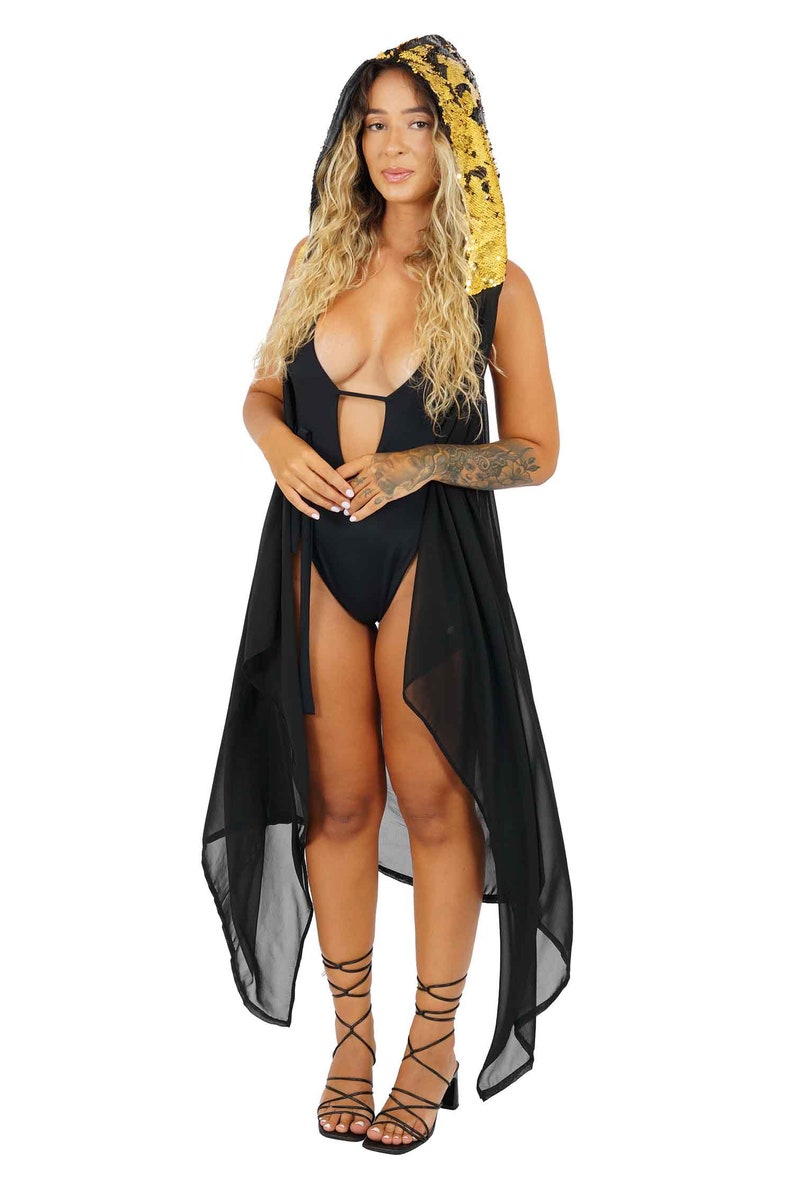 May include: A black sheer cover-up with a gold sequined hood. The cover-up is long and flowing, and the hood is attached to the back of the neck. The cover-up is worn over a black swimsuit.