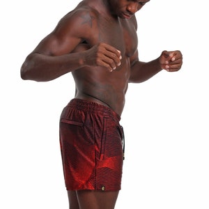 May include: A man wearing red and black patterned athletic shorts. The shorts have a drawstring and a side pocket.