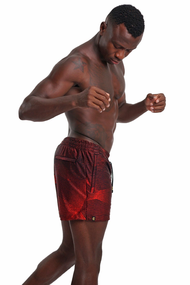 May include: A man wearing red and black patterned athletic shorts. The shorts have a drawstring and a side pocket.