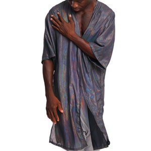 K&ouml;nnte beinhalten: Eine Person tr&auml;gt eine lange, schimmernde silberne und schwarze Robe mit einem langen, flie&szlig;enden Design. Die Robe ist vorne offen und zeigt die Brust und die Arme der Person.