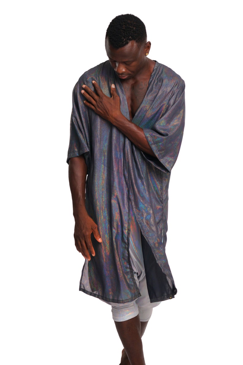 K&ouml;nnte beinhalten: Eine Person tr&auml;gt eine lange, schimmernde silberne und schwarze Robe mit einem langen, flie&szlig;enden Design. Die Robe ist vorne offen und zeigt die Brust und die Arme der Person.