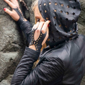 Soft black leather hand bracelet embellished with metal studs and wrist metal buttons to fasten. Black fingerless gloves, festival wear punk, emo, and rock n roll style accessories.