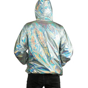 Silver waterproof holographic windbreaker for men. A loose-fit rave jacket with white thumbhole cuffs, full-zip front, and hood by Love Khaos