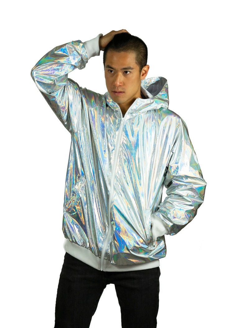 Silver waterproof holographic windbreaker for men. A loose-fit rave jacket with white thumbhole cuffs, full-zip front, and hood by Love Khaos