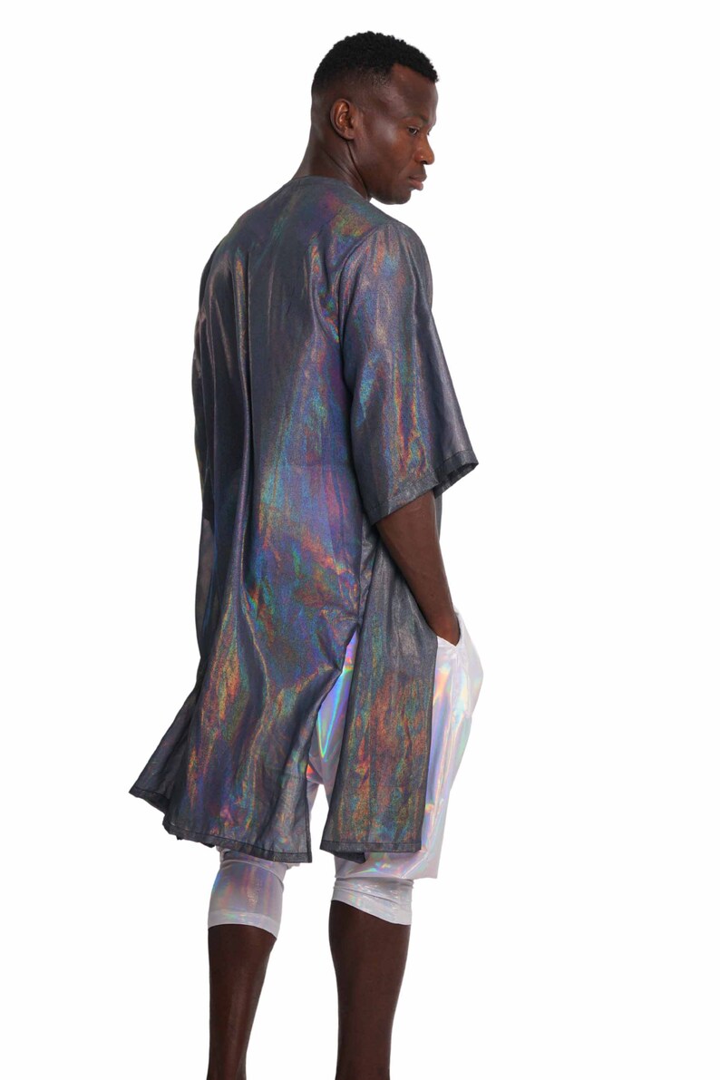 K&ouml;nnte beinhalten: Ein lang&auml;rmeliges, irisierendes Hemd mit schwarzer Basis und holografischem Finish. Das Hemd hat eine lockere Passform und eine etwas l&auml;ngere L&auml;nge. Das Model tr&auml;gt das Hemd mit einer irisierenden Leggings.