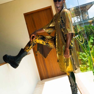 K&ouml;nnte beinhalten: Eine Person tr&auml;gt einen goldenen Pailletten-Kimono mit schwarzen und gelben Leggings mit Flammenmuster und schwarzen Plateau-Stiefeln.