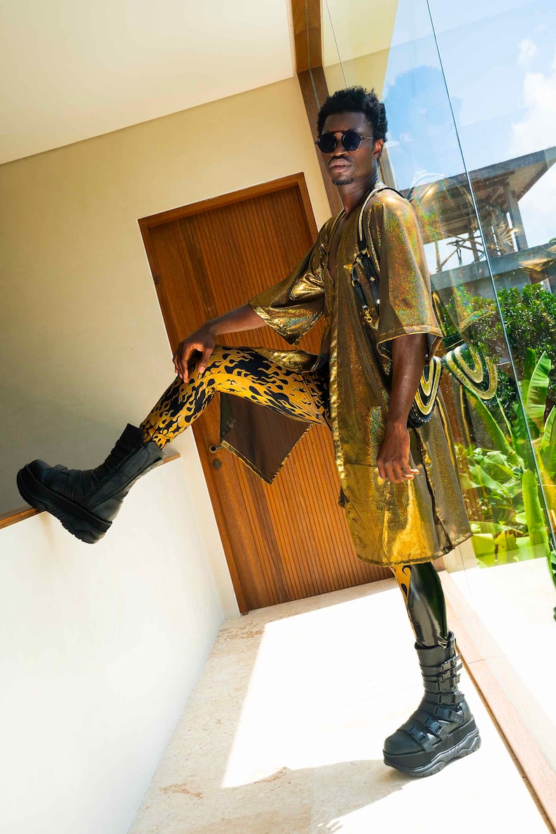 K&ouml;nnte beinhalten: Eine Person tr&auml;gt einen goldenen Pailletten-Kimono mit schwarzen und gelben Leggings mit Flammenmuster und schwarzen Plateau-Stiefeln.