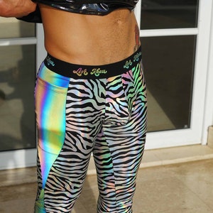 May include: Black and white zebra print leggings with a rainbow iridescent panel on the side. The leggings have a black waistband with the text "Love Kings" printed on it.