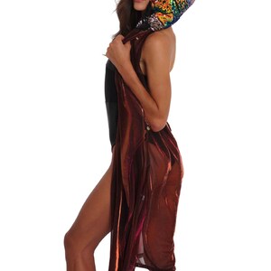 May include: A woman wearing a burgundy sheer long-sleeved top with a sequined rainbow-colored hood.