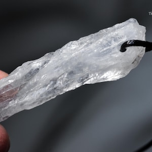 May include: A clear, raw crystal pendant with a black cord. The crystal is irregularly shaped and has a rough, textured surface. The Healing Sea Wolf is written in the top right corner.