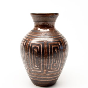 May include: A brown ceramic vase with a geometric pattern. The vase has a wide body and a narrow neck. The pattern consists of repeating black and brown squares and lines. The vase is approximately 25 cm tall.