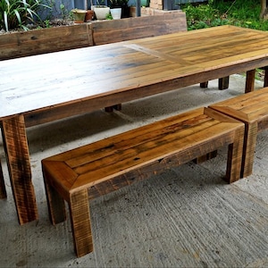 May include: A rustic wooden dining table set with two benches and a stool. The table is made of reclaimed wood and has a natural finish. The benches and stool are also made of reclaimed wood and have a natural finish.