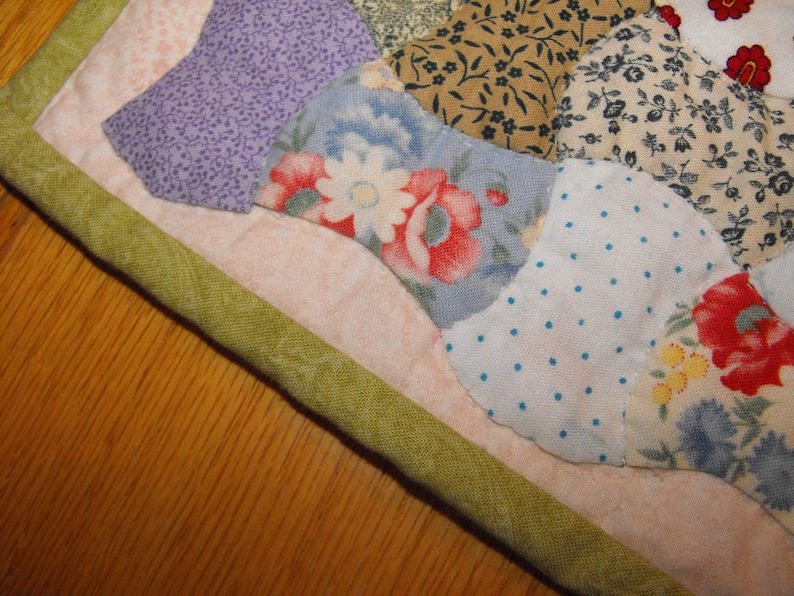 May include: A patchwork quilt with a green border and a variety of floral patterns in shades of blue, pink, white, and green.