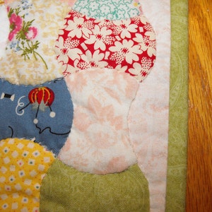 May include: A patchwork quilt with various floral and geometric patterns in shades of blue, red, yellow, and green. The quilt is made of different fabrics sewn together to create a unique design.