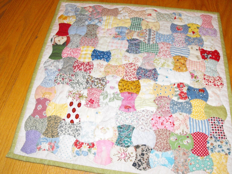 May include: A patchwork quilt with a variety of floral and geometric patterns in shades of pink, blue, yellow, green, and red. The quilt is made up of individual squares sewn together to create a larger design.