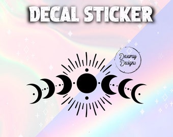 Puede incluir: Adhesivo negro con un diseño celestial que muestra las fases lunares y un sol central. El texto "DECAL STICKER" está en la parte superior y "SWIPE TO SEE MORE" en la inferior. El diseño está sobre un fondo pastel.