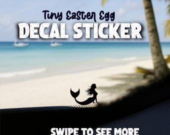 May include: A black decal sticker with a mermaid silhouette, the text "Tiny Easter Egg DECAL STICKER", and "SWIPE TO SEE MORE" against a beach backdrop with boats and palm trees.