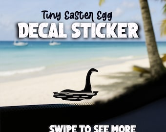 May include: Black decal sticker featuring a silhouette of the Loch Ness Monster in water. The text "Tiny Easter Egg DECAL STICKER" is above the image. The words "SWIPE TO SEE MORE" are at the bottom.