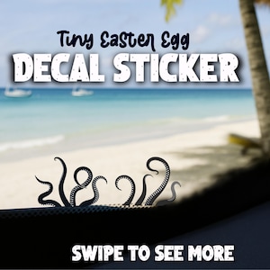 以下が含まれることがあります： スタイリッシュなタコの触手を描いた黒いデカールステッカー。「Tiny Easter Egg DECAL STICKER」の文字が上に表示されています。「SWIPE TO SEE MORE」の文字が下にあります。背景にはビーチの風景が描かれています。