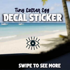 May include: A decal sticker with the text "Tiny Easter Egg DECAL STICKER" in white letters. Below the text is a black and white eye graphic. The background shows a beach scene with the text "SWIPE TO SEE MORE".
