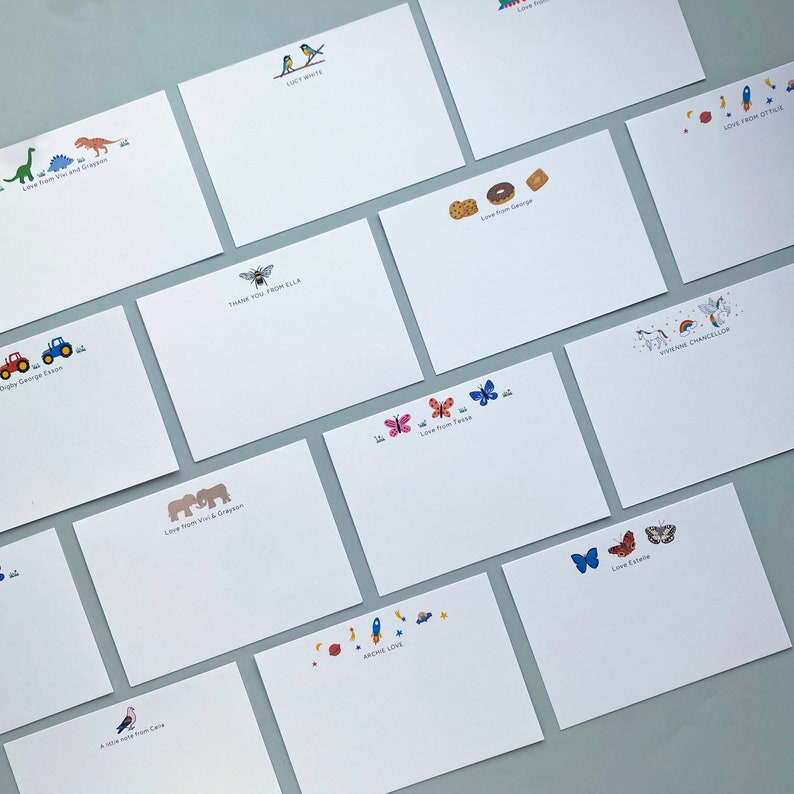 May include: A set of blank note cards with various illustrations and personalised messages. The illustrations include a dinosaur, a bee, a tractor, elephants, butterflies, a rocket, a unicorn, and birds. The messages include "Love from Viv & Grayson", "Thank you from Ella", "Love from George", "Love from Ottilie", "Love from Tessa", "Love Estelle", "A little note from Cora", "Digby Denise Easton", "Love from our and Grayson", "Lucy White", "Everything Chancellor", "Archie Love".