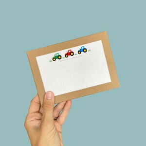 May include: A brown card with a white border and a line of four cartoon tractors in green, red, and blue. The text "GRAYSON CHANCELLOR" is printed below the tractors.
