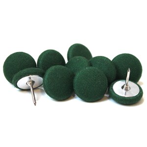 Può includere: Un set di dieci puntine da disegno rivestite in tessuto verde scuro con basi e puntine in metallo argentato.