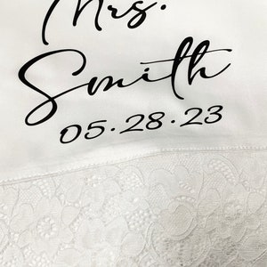 May include: White satin robe with black lace trim and the text "Mrs. Smith 05.28.23" embroidered on the front.