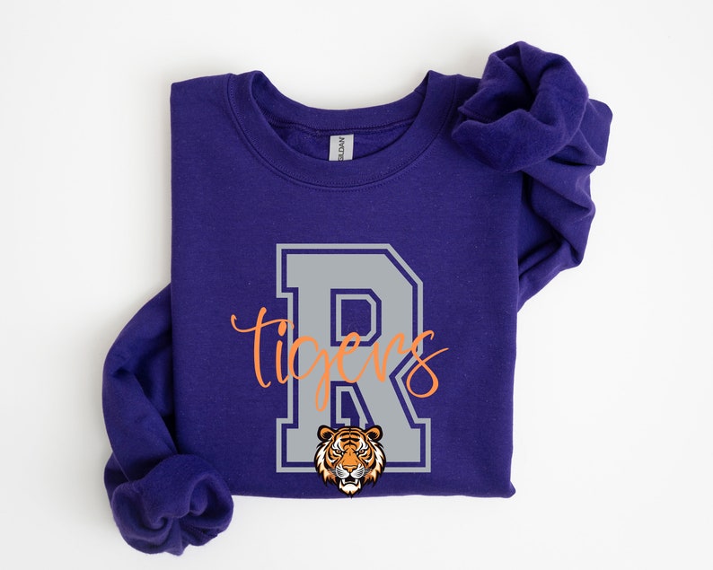 May include: Purple sweatshirt with a gray letter R and the word "tigers" in orange script. A tiger head is inside the letter R.