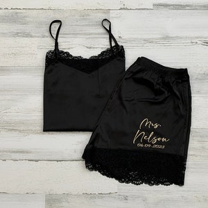 May include: Black satin pajama set with lace trim. The shorts have the text "Mrs. Nelson 06.09.2023" embroidered in gold.