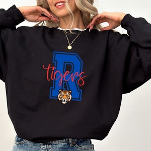 May include: Black sweatshirt with a blue and white letter "R" and the word "Tigers" in red. A tiger head is inside the letter "R".