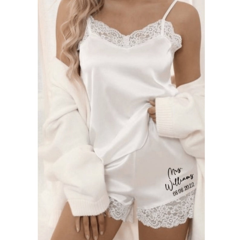 May include: White satin pajama set with lace trim. The shorts have the text "Mrs. Williams 08 08 2022" printed on them.