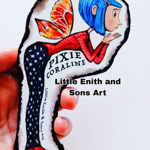 May include: A hand-painted art piece featuring a cartoon character with blue hair, red top, and star-patterned pants. The character has orange and red wings and the text "Pixie Coraline". The art is signed "Little Enith & Sons Art".