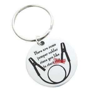 May include: A silver keychain with a round tag that says "Here are some jumper cables since you like to start [CENSORED]" with a black and white illustration of jumper cables.