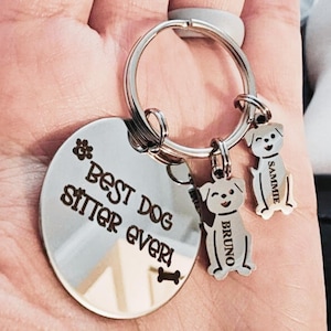 May include: A silver keychain with a large round tag that reads "Best Dog Sitter Ever" and a paw print and bone graphic. Two small dog-shaped charms are attached, each with a name: "Bruno" and "Sammie".