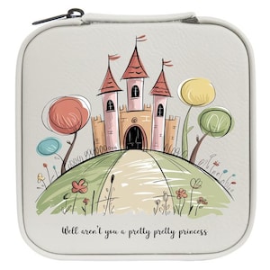 May include: A square, light gray zippered case featuring a whimsical illustration of a pink castle on a green hill with stylized trees and flowers. The text "Well aren't you a pretty pretty princess" is printed in black script at the bottom.