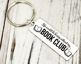 May include: A silver rectangular keychain with a silver ring. The keychain has the text "Life would be boring without my BOOK CLUB" in black, with book illustrations on each side.