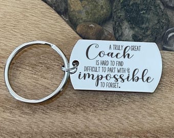 May include: A silver-toned metal keychain with a rectangular tag featuring the engraved black text: A TRULY GREAT Coach IS HARD TO FIND DIFFICULT TO PART WITH & impossible TO FORGET. The tag is attached to a circular metal split ring.