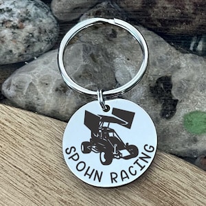 May include: Silver keychain with a black silhouette of a race car and the text "Spohn Racing".
