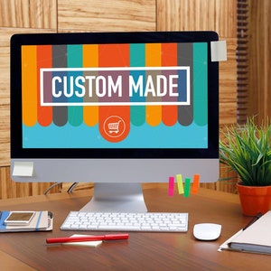 May include: A computer monitor displaying a colorful graphic with the text "CUSTOM MADE" and a shopping cart icon. The monitor is on a wooden desk with a keyboard, mouse, and other office supplies.