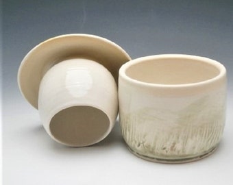 May include: A white ceramic butter dish with a lid. The dish has a textured, green glaze on the outside. The lid is smooth and white.
