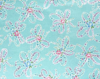 May include: A repeating floral pattern on a light blue background. The design features stylized flowers with pink, purple, and blue blossoms, connected by white ribbon-like elements. The overall effect is delicate and vintage.