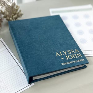 Personalized wedding planner binder to organize your entire wedding in one place — includes all checklists, timelines, budget sheets, and vendor contract sections. Fully customizable cover and spine colors with your names, wedding date, or custom text. Perfect keepsake for brides and wedding planners to stay organized from engagement to wedding day.