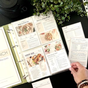 An opened binder showing transparent sleeves of recipe cards in 4x6 inch or 10x15 cm size. There are printed recipe cards as an example. A4 size binder with 4 rings.