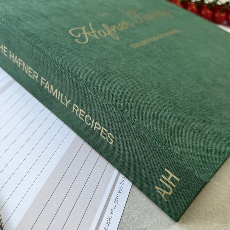 Dark green recipe book with custom text in gold color on the cover.  The book is thick and has a luxurious feel. It's a high-quality, personalized recipe book for storing family recipes.