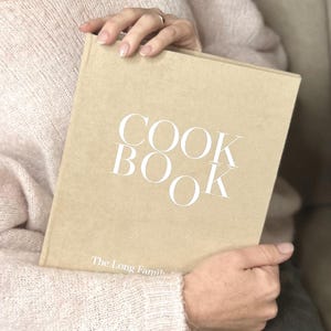 A Beige color recipe binder book with white text in hands.
