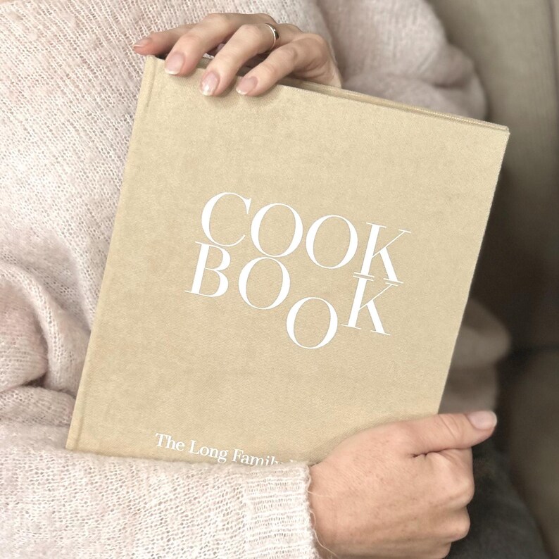 A Beige color recipe binder book with white text in hands.
